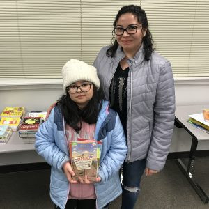 Hayry and Keylin receive a stack of brand new children's books for their home library donated during the 2019 Giving Tree Book Drive.