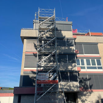 Tour d’accès avec barrières de toit installées pour sécuriser l’installation de panneaux photovoltaïques sur un petit immeuble à Porrentruy, canton du Jura.