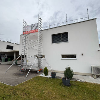 Lift de chantier et barrières de toit avec plots lestés installés sur une toiture plate à Courfaivre, canton du Jura, pour sécuriser la pose de panneaux solaires photovoltaïques.