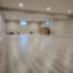 Spacious basement with light wood flooring, a central support column, bar counter, shelves, small windows, and lawn equipment on the side.