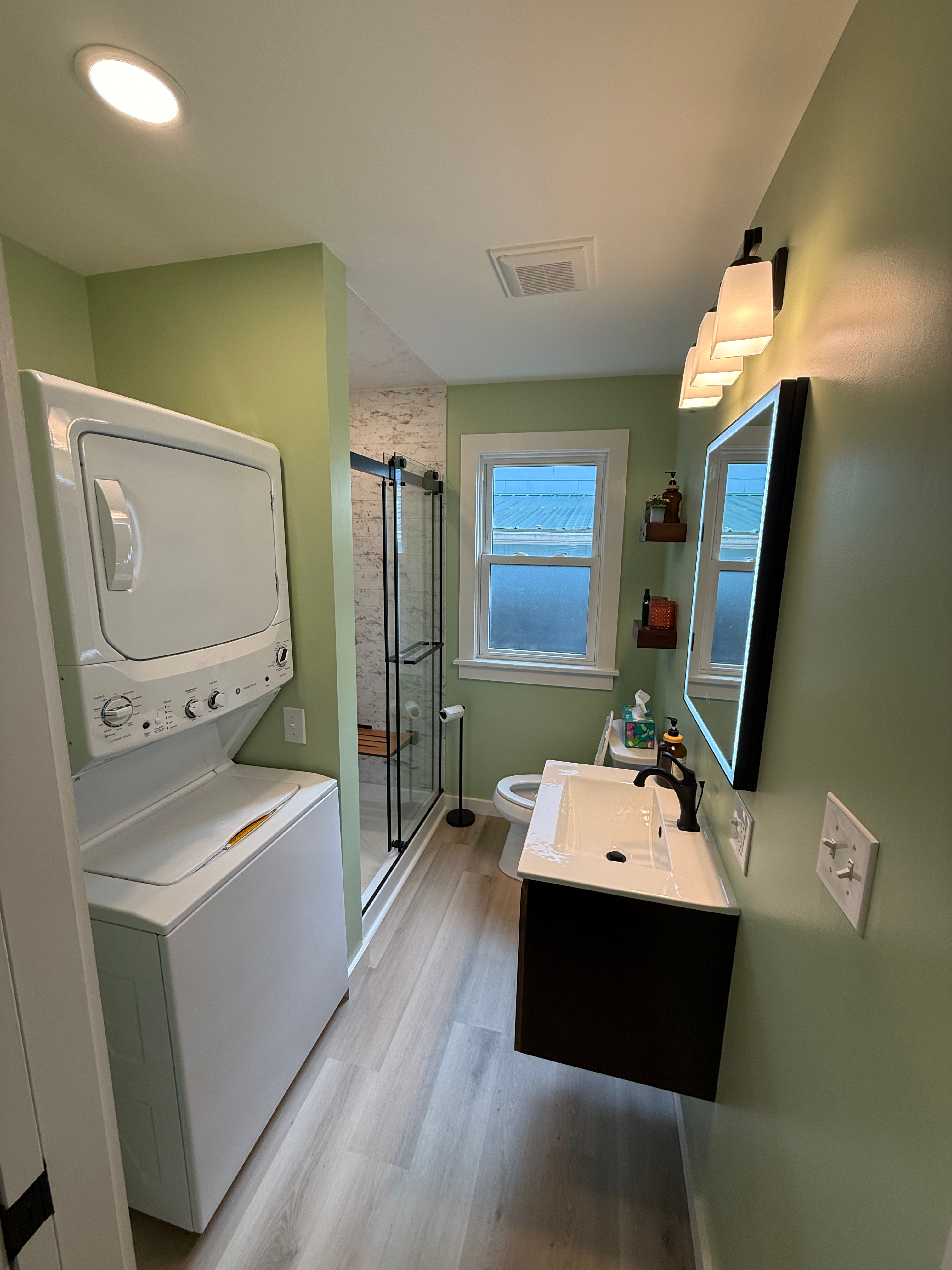 Completed JM bathroom with glass shower, green walls and wood vanity