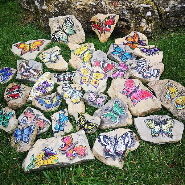 Feldsteine im Gras, die mit Schmetterlingen bemalt sind
