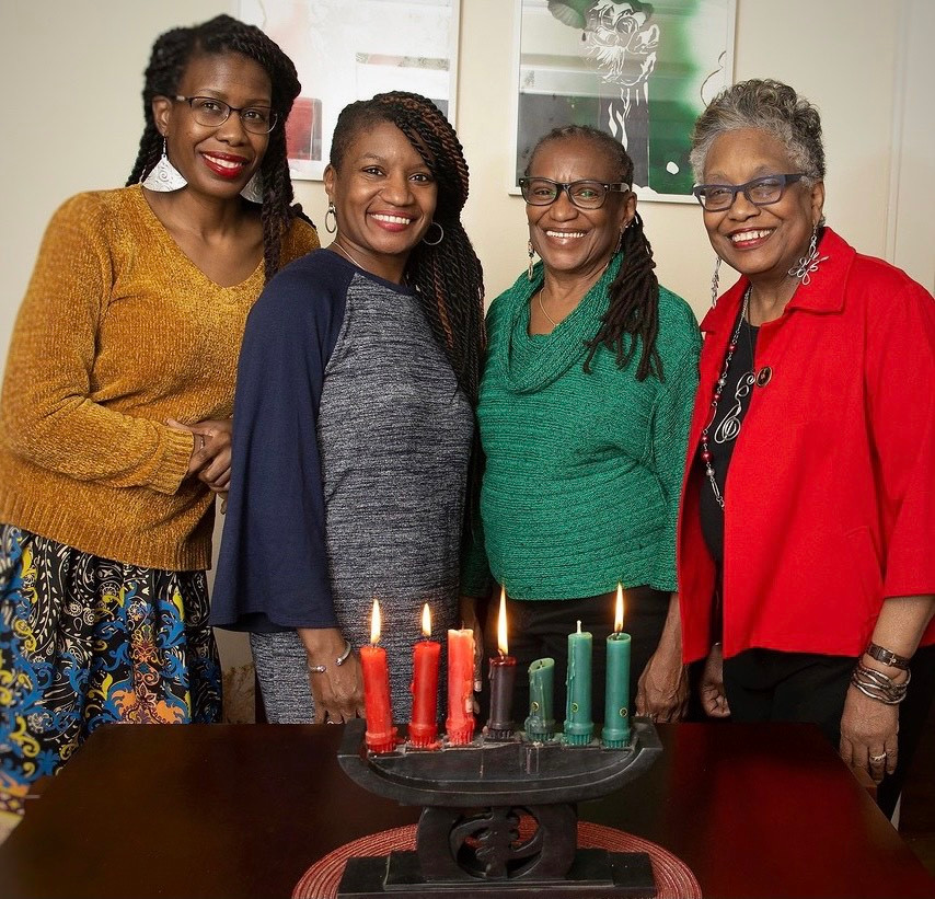 Author and family standing at a table with a lit kinara in the center