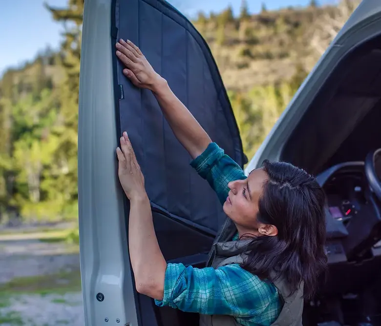 Woman installing van window shade outdoors