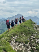 Wandergruppe von hinten auf einem Grat in den Alpen