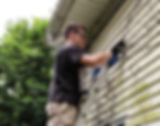 Picture of Charles Lake on a ladder painting the exterior of a house