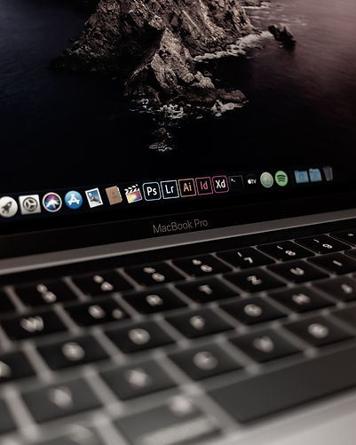 Black and white closeup on a MacBook Pro with a colourful Adobe taskbar.