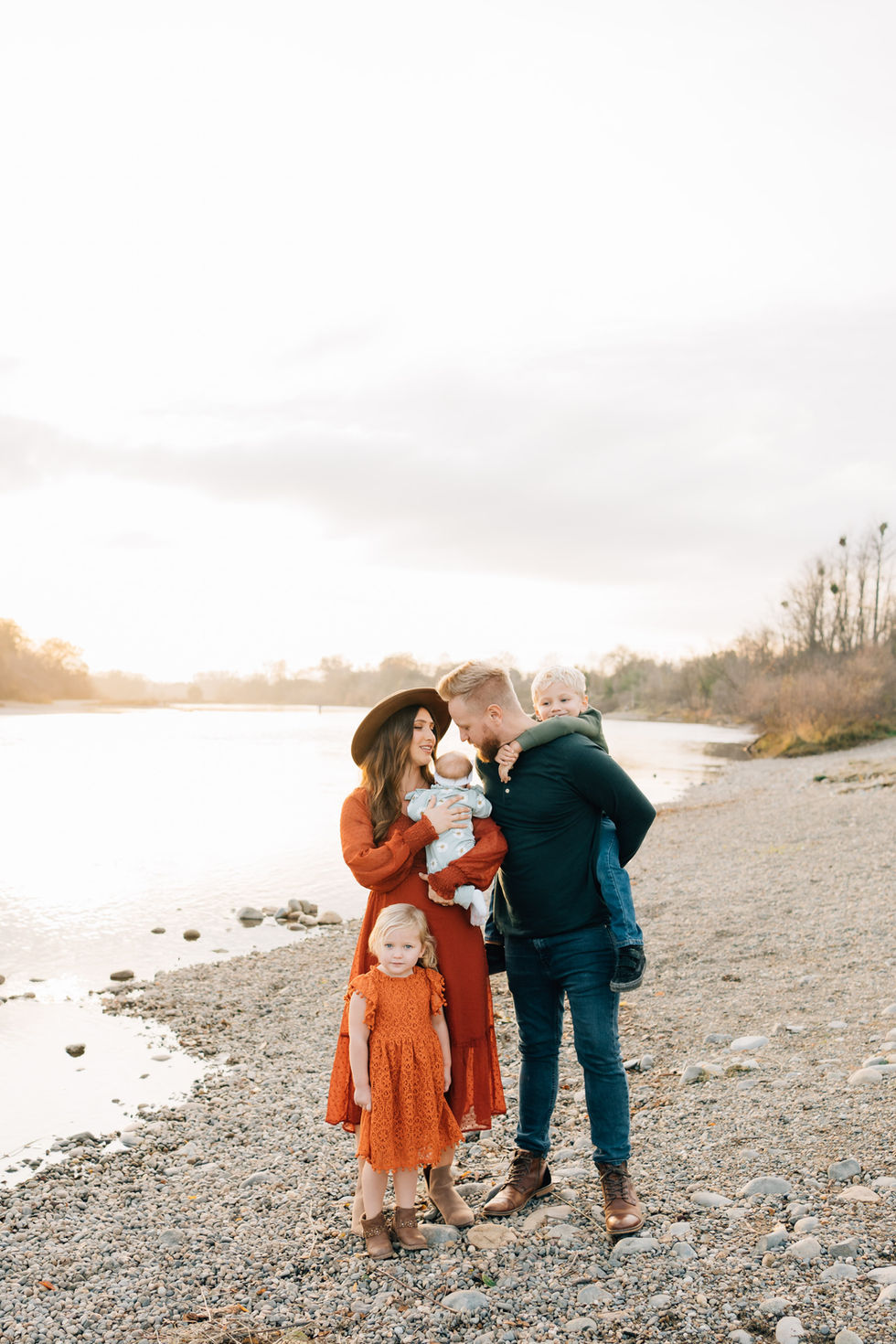 A family of five standing next to a river during sunset