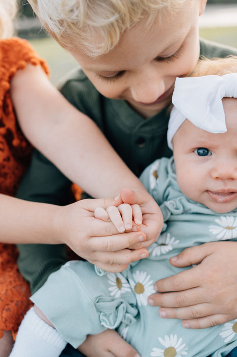 A brother and sister holding hands with their little sister