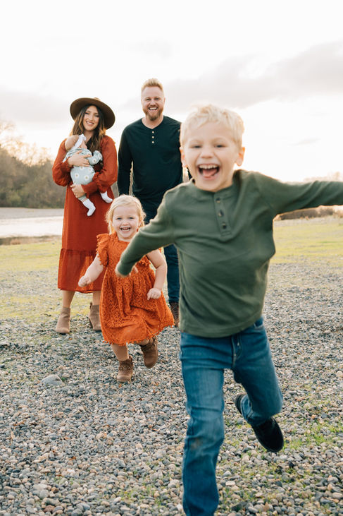 A boy and a girl running towards a camera in front of mom and dad