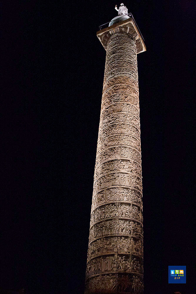 Tall, intricately carved column with a statue on top against a dark sky. The scene is dramatic and majestic, evoking historical grandeur.