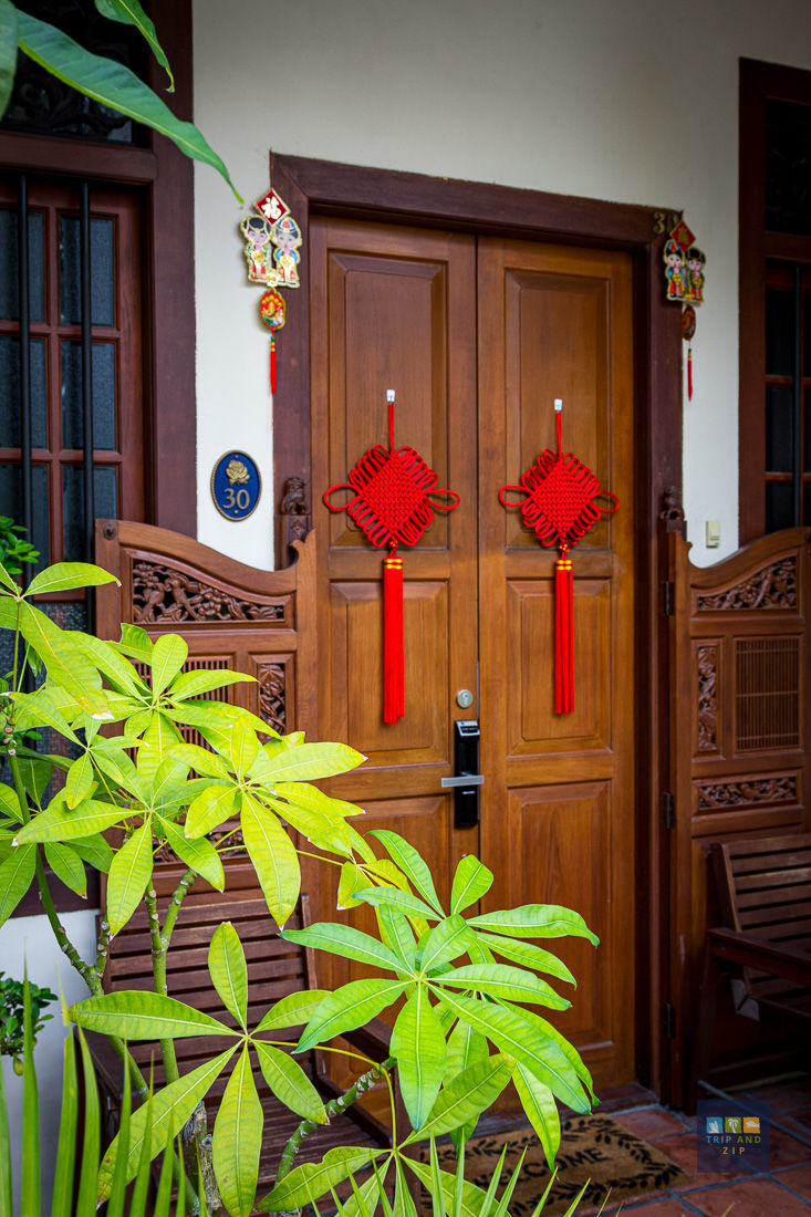 Wooden door with red Chinese knots, door number 30. Green leafy plant in foreground, decorative carvings, festive mood.
