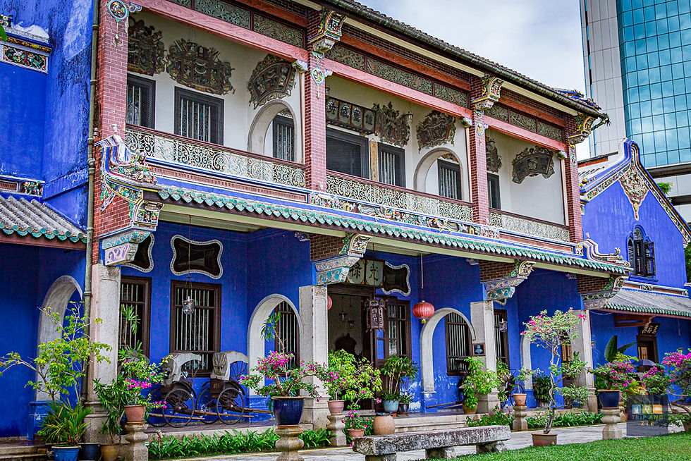 Ornate blue heritage building with intricate patterns, potted plants, and a rickshaw on the patio. Red lanterns add color. Peaceful setting.
