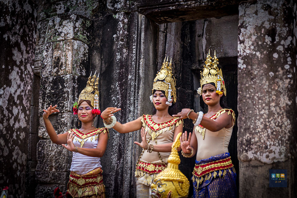Three dancers in ornate gold headdresses perform gracefully against ancient stone ruins; vivid costumes with red and gold accents convey cultural elegance.