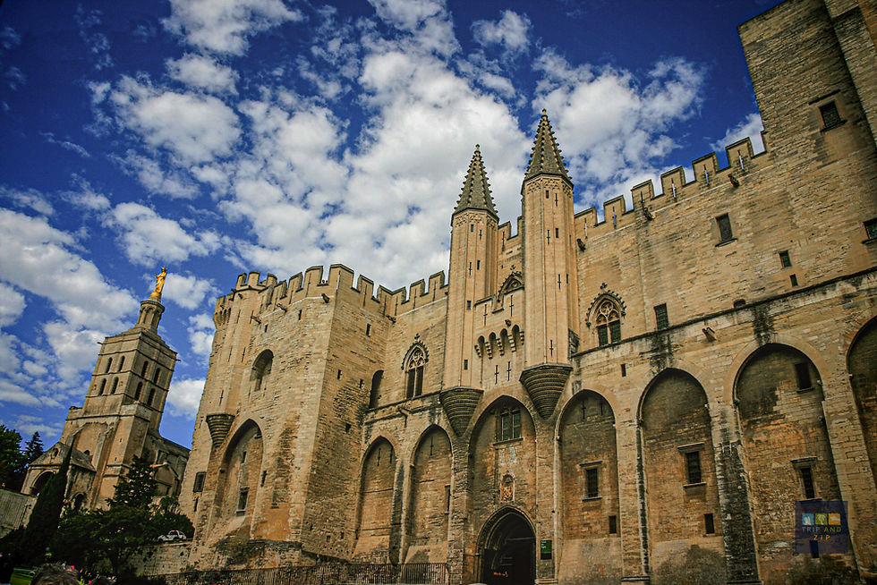 Gothic castle with ornate towers under a blue sky with clouds. A golden statue is visible on the left. Mood is historic and majestic.