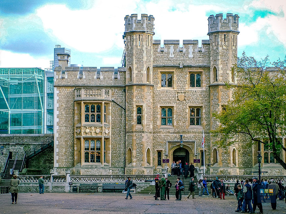 Historic stone building with turrets set against a cloudy sky. People gather in front, some taking photos. Tree on the right, modern glass on the left.