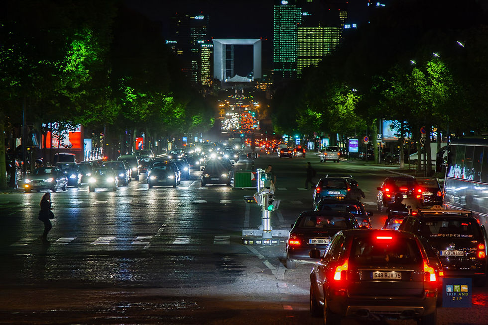 Night cityscape with busy traffic under glowing streetlights. Cars line the road, and skyscrapers loom in the background, creating an urban vibe.