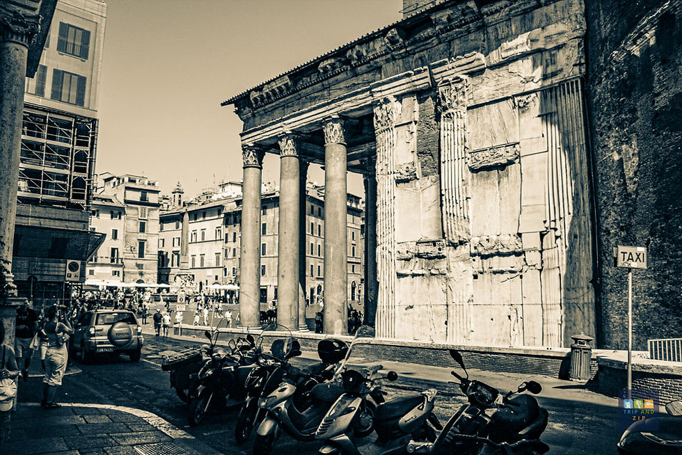 Ancient Roman columns stand in a bustling street, with scooters parked nearby. A sign reads "TAXI." Sepia tones give a nostalgic feel.