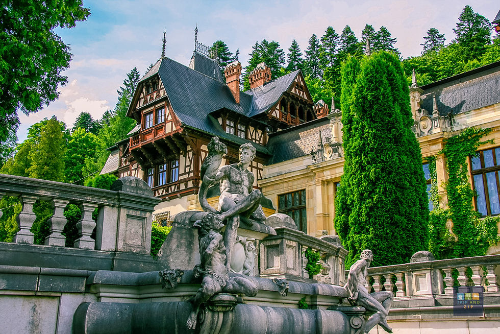 Ornate stone statues in front of a Tudor-style building with ivy, surrounded by lush greenery and tall trees under a blue sky.