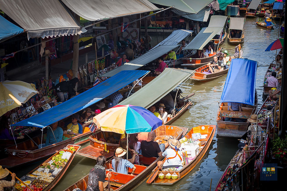 Crowded floating market with boats carrying colorful umbrellas and goods. People shopping along the canal under shaded stalls. Vibrant scene.