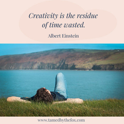 A man lying on a patch of grass near a water body.