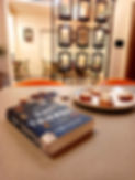 In a cafe, a copy of The Day Tripper by James Goodhand lies on a table next to a plate of mushroom crostini. Photo by Ninay Desai.