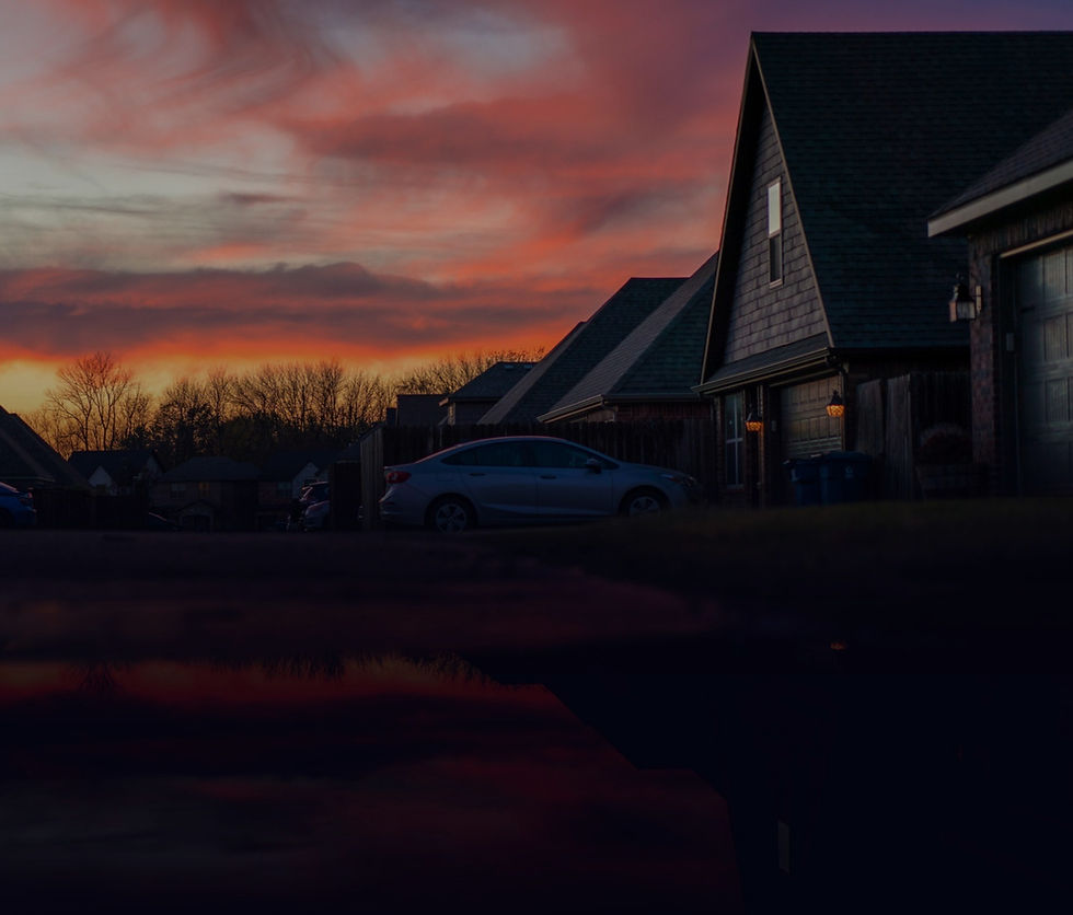 Homes in the neighborhood as the day draws to a close. The houses are deeply shadowed by a brilliant late fall sunset with vibrant red, orange and violet hues.