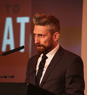 Mark Franklin on stage speaking at a lecturn. he has a tear in his eye