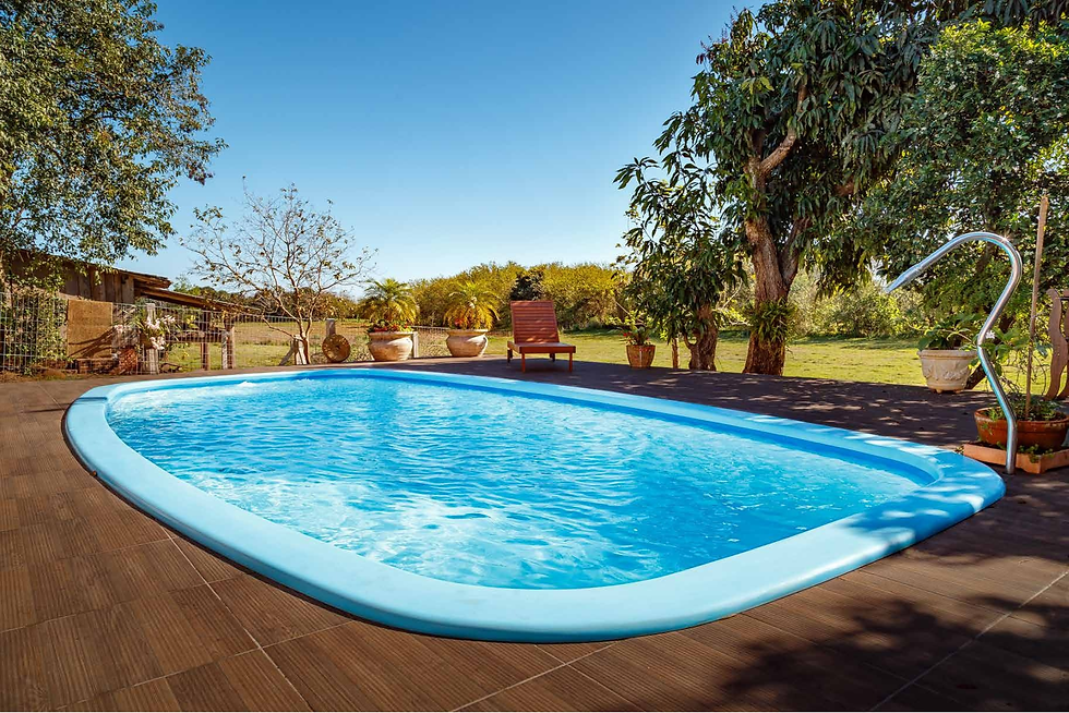 Piscina azul em um quintal com árvores e vasos. Espreguiçadeira ao fundo. Céu claro e ambiente tranquilo.