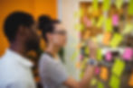 Duas pessoas escrevendo em postits num processo de design thinking