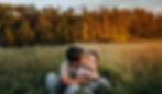 Two brothers hugging and sitting in field during sunset