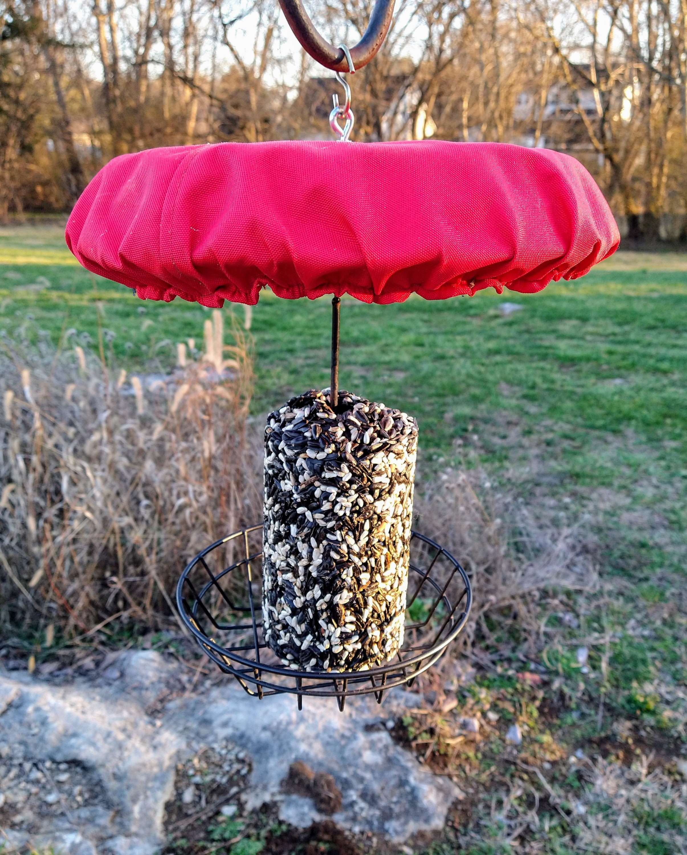 Red canvas rain and snow guard protecting seed cylinder feeder