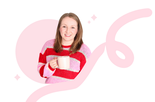 Carys is looking at the camera, smiling. She is holding a cup of tea, and wearing a pink and red striped jumper. 