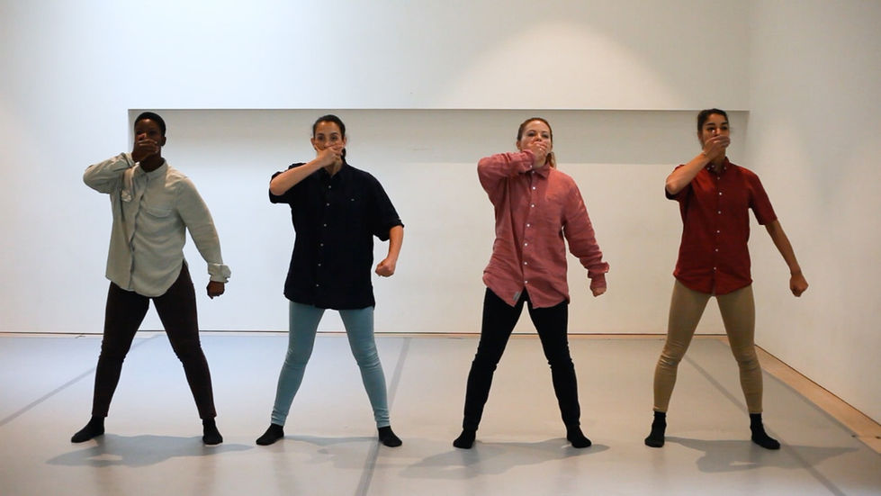 Four dancers stand in a line, one arm at their side and the other covering their mouth
