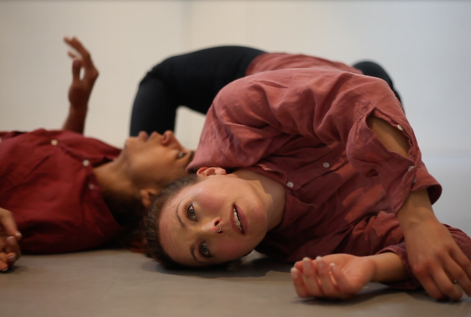Connect - climate arts spoken word and dance film.One dancer is on the floor with her hips up and twisted so as to lean on one shoulder, while another dancers lies on her back underneath her