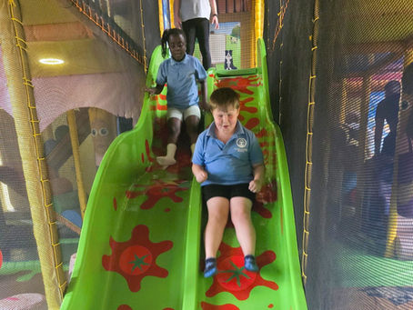 Two pupils from Pine class playing on a giant slide at Sprouts Play Barn