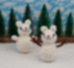 A photo of two knitted snowmen mice, one with chubby snow arms and one with stick arms.