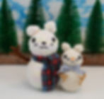 A photo of two knitted snowmen mice, one a head taller than the other.
