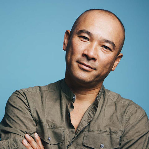 Headshot, portrait, from shoulders up. Clean shaven. Dark olive green shirt. Head gently tilted to the side.