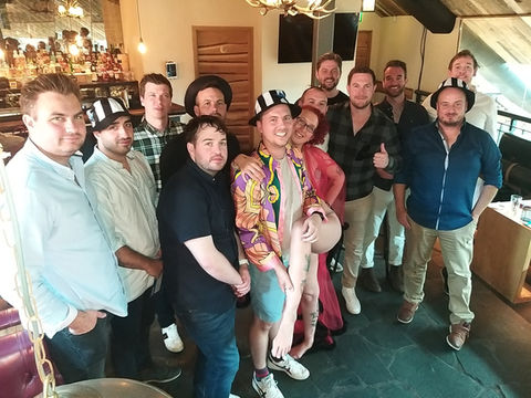 Stag party group posing with burlesque performer in bar venue