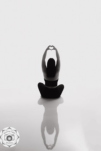 A yoga instructor performing a stretching pose on a mat in a bright studio.