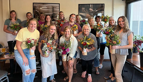 roup of ladies holding bouquets they made at Bremer Brewing Company in Waverly, Iowa, smiling and enjoying their creative event.