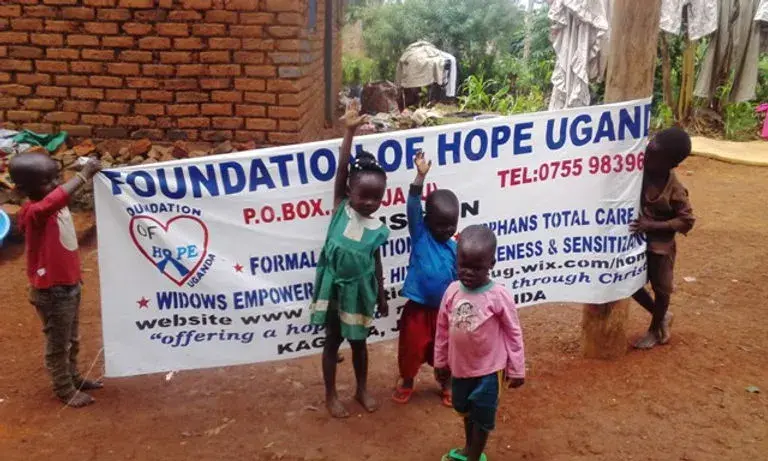 Children in front of the newly created “Foundation of Hope,” holding a sign