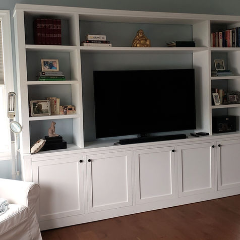 Custom white built‑in wall unit with shelving, cabinetry, and integrated entertainment center in Miami home by Optimum Builders