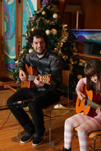 Guitar instructor teaching a child beginner guitar techniques during a cozy holiday-themed lesson at Mermi Music Academy in North Vancouver