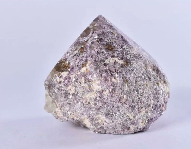single polished lepidolite point on a white background