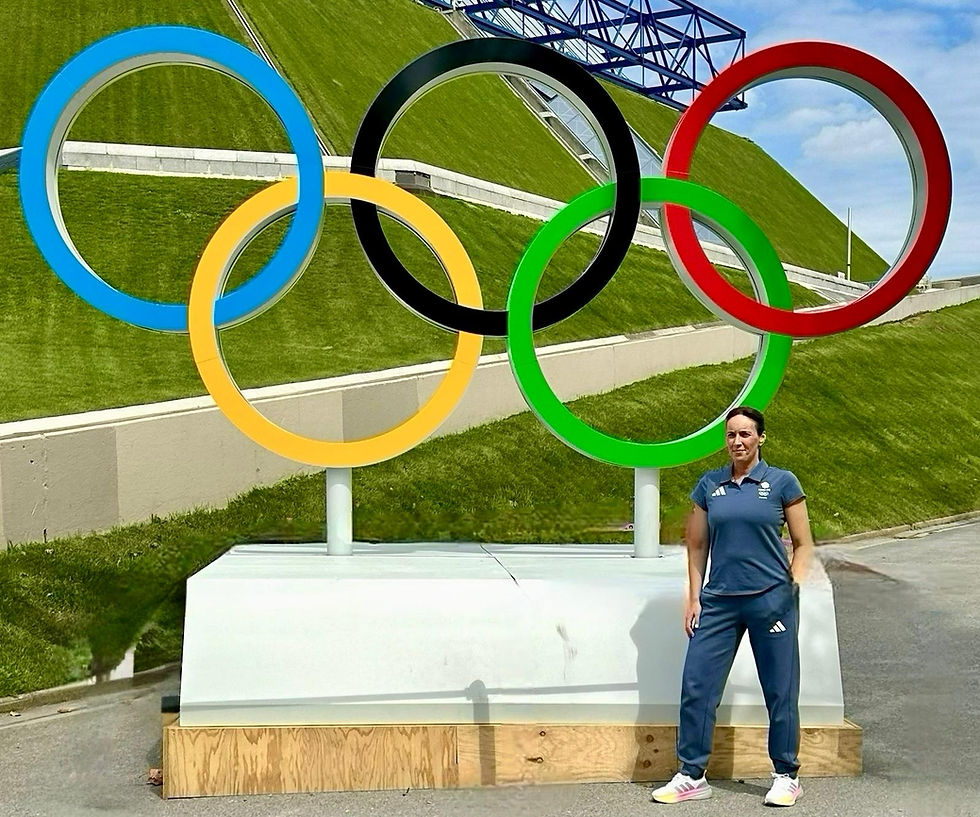 Athlete in blue tracksuit standing by Olympic rings