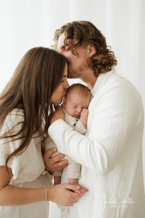 nouveau-né dans les bras de papa et maman donne un bisou. Papa donne un bisou à maman.