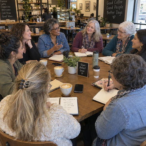 group of eight casual women sitting around a table at a coffee store sharing and journalin