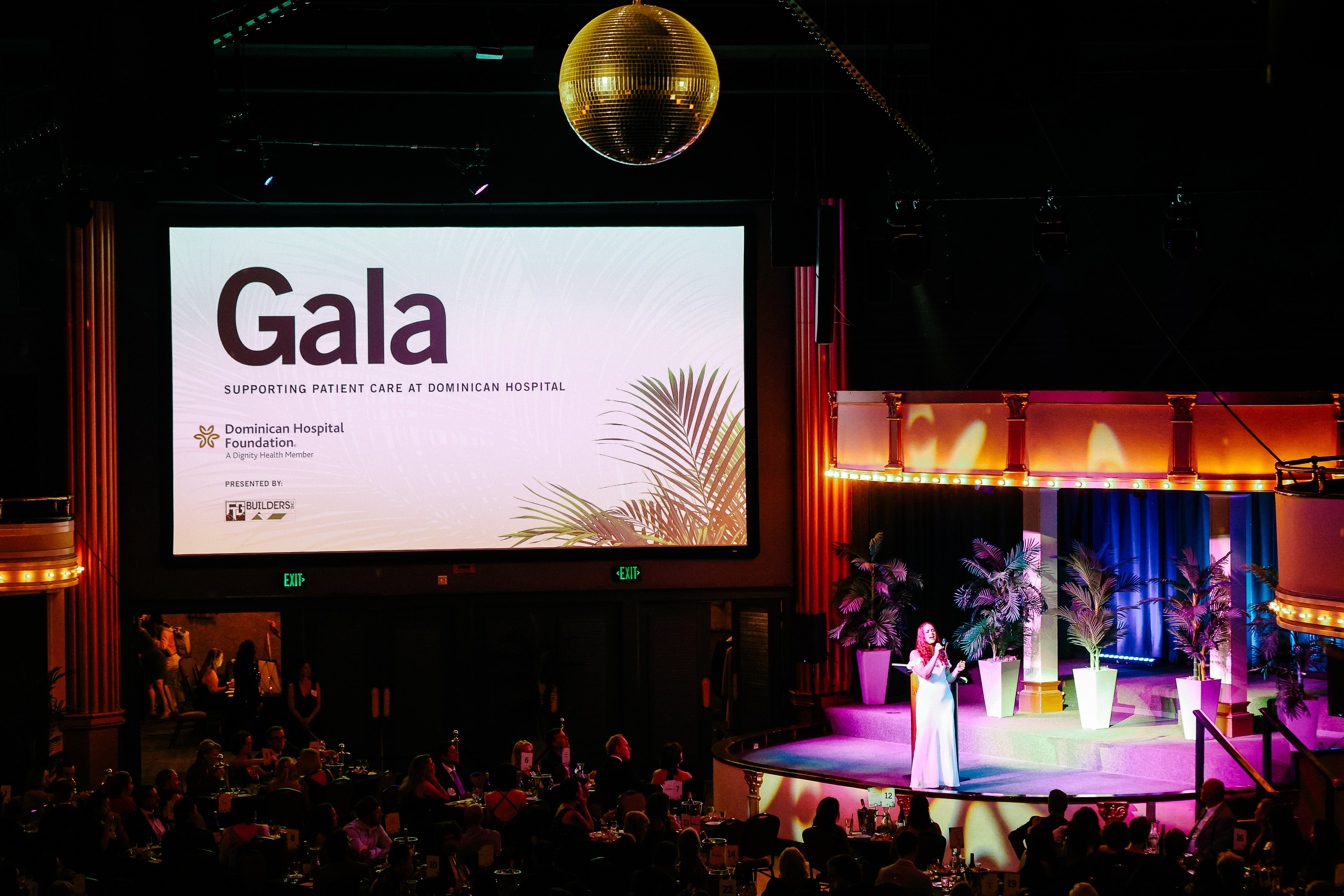 Speaker on a lit stage beneath a screen reading Gala